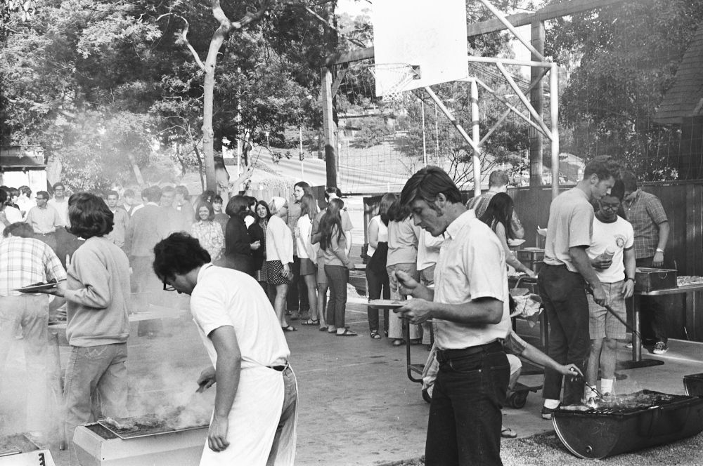 A crowd waits for food from the grill in the courtyard.